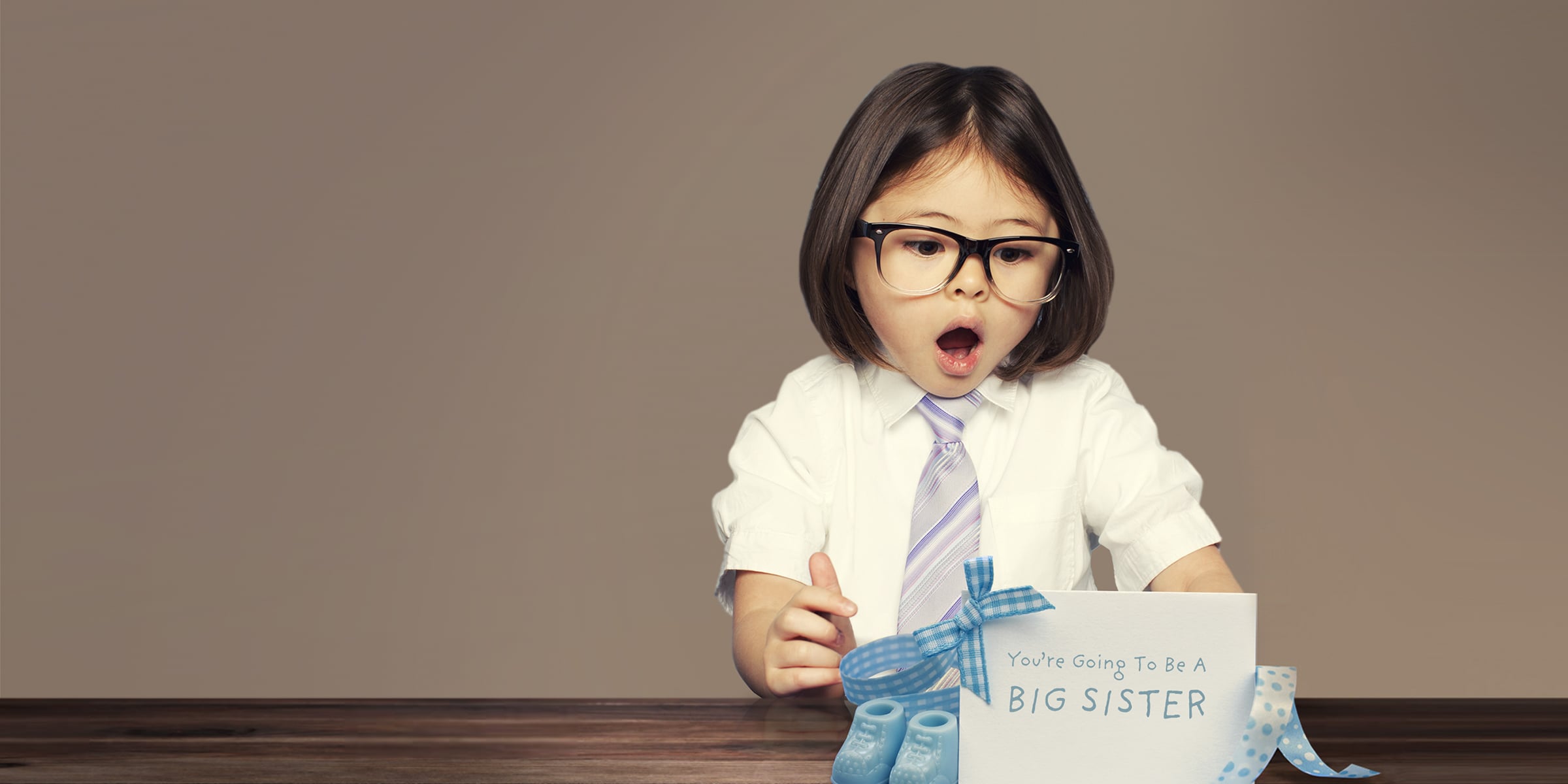 Girl in white shirt, tie, and large glasses looks surprised looking at card that says 