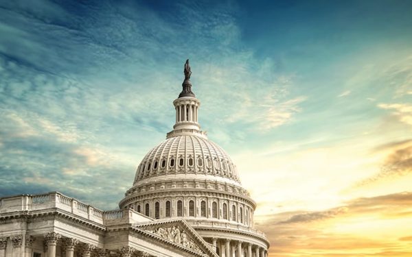 The top of the Capitol Building against a blue and gold sky.