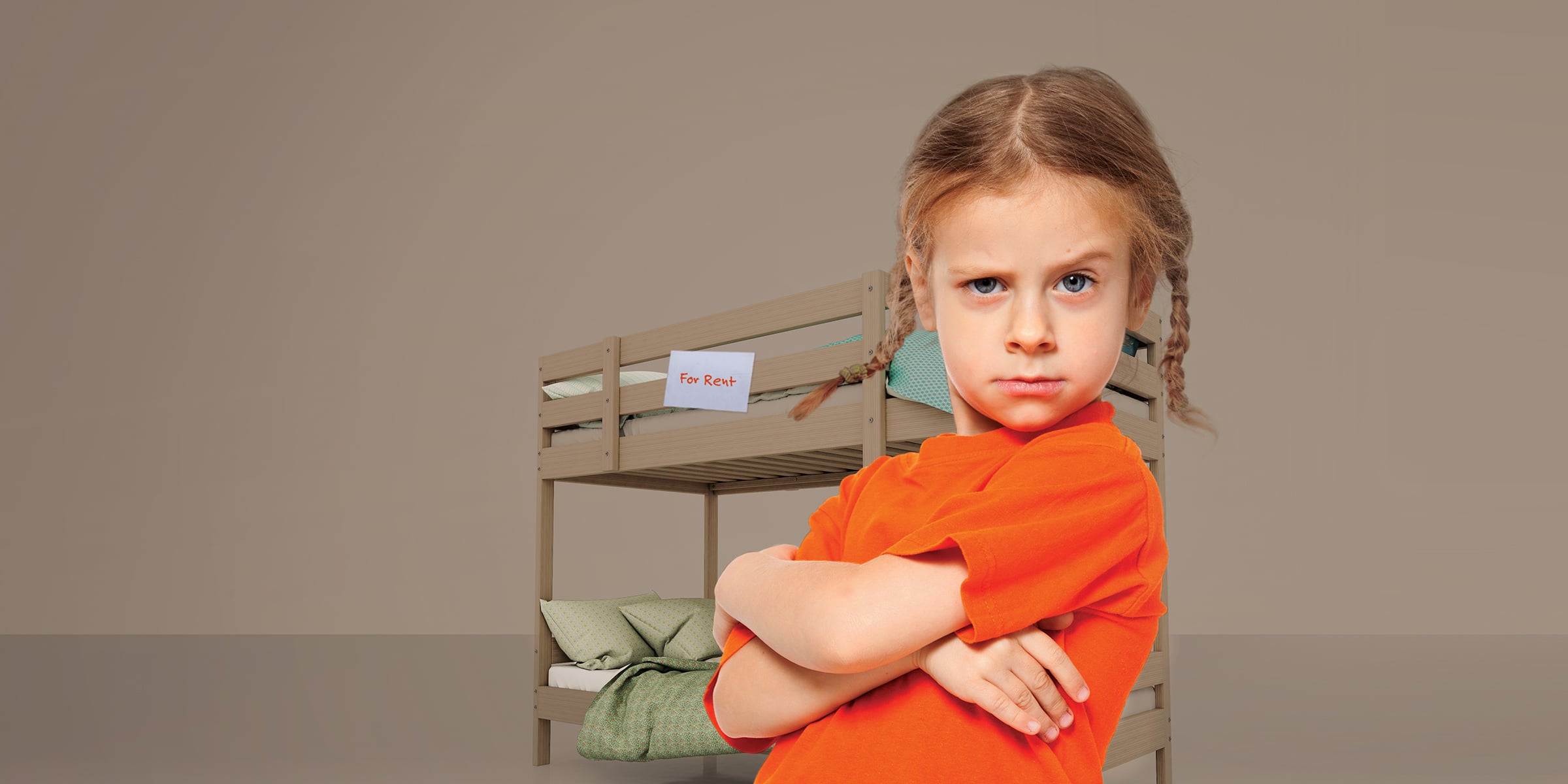 Child with braided pigtails in orange shirt crosses her arms in front of a brown bunkbed with a 