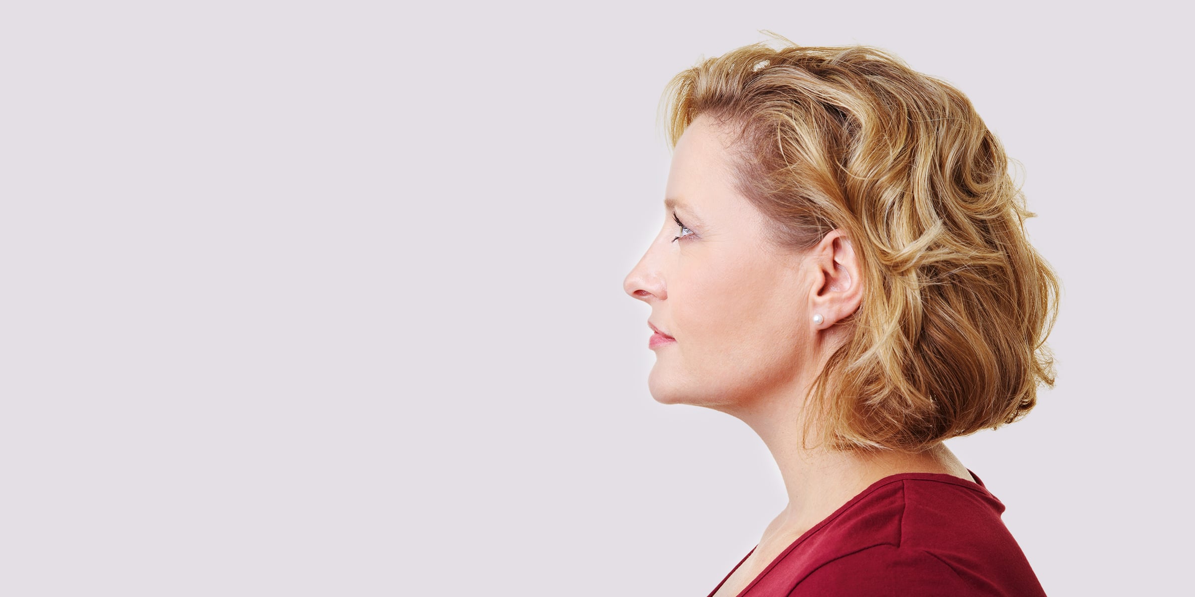Profile of a blonde wavy-haired woman in a red shirt.