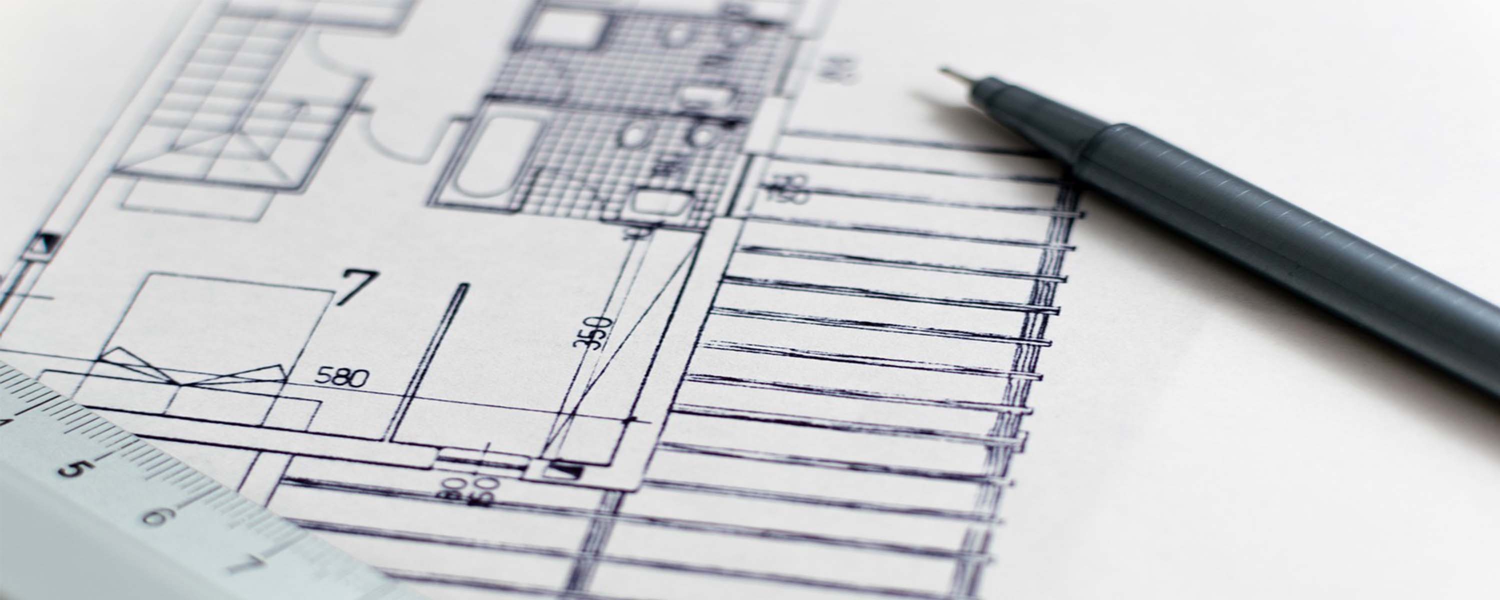 Blueprint with pen and ruler sitting on top of it.