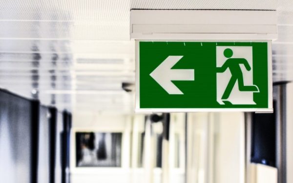 Green sign with a stick figure running and an arrow pointing to the left.