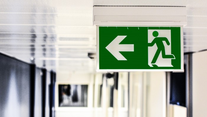 Green sign with a stick figure running and an arrow pointing to the left.