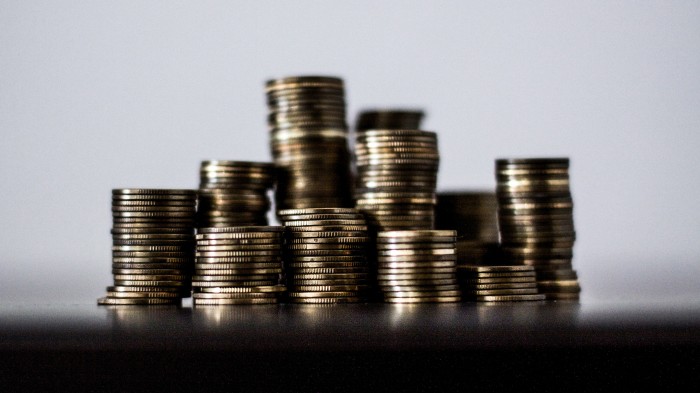 Multiple stacks of coins sitting on a blurry surface.