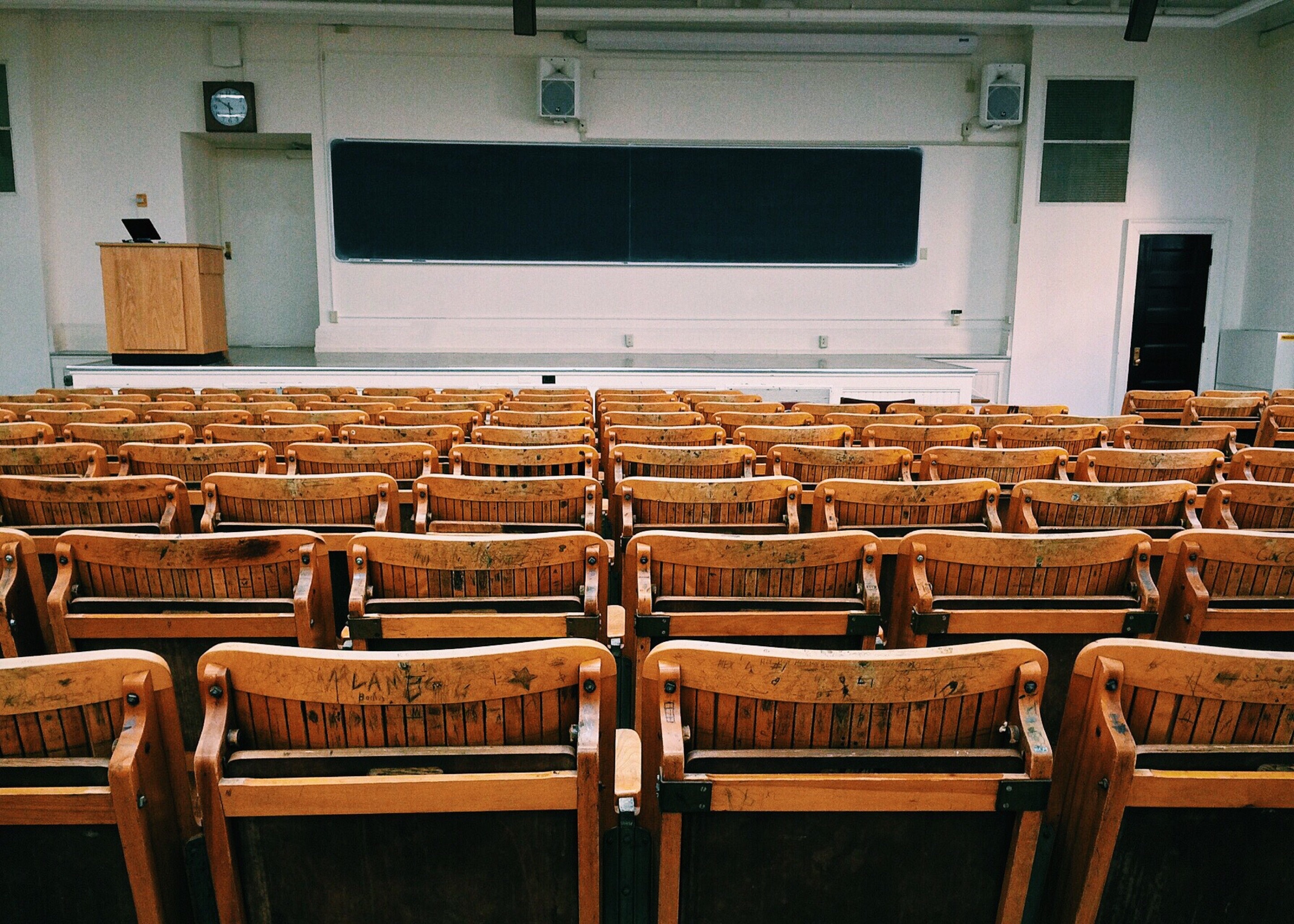 Empty lecture hall with wooden seats.