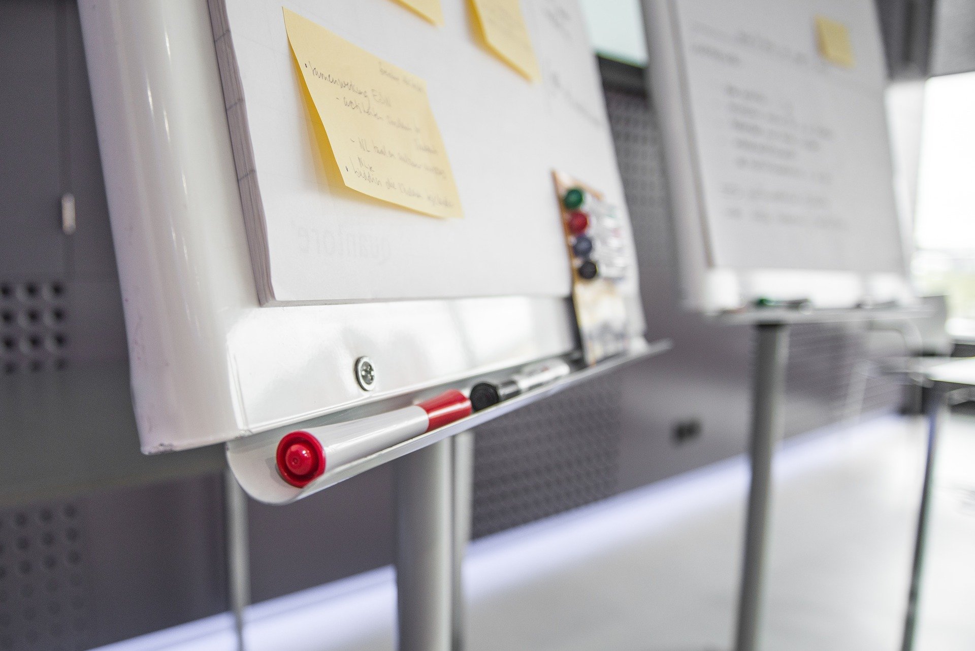 Two whiteboards with dry erase markers sitting on their ledges and post-its on their boards.