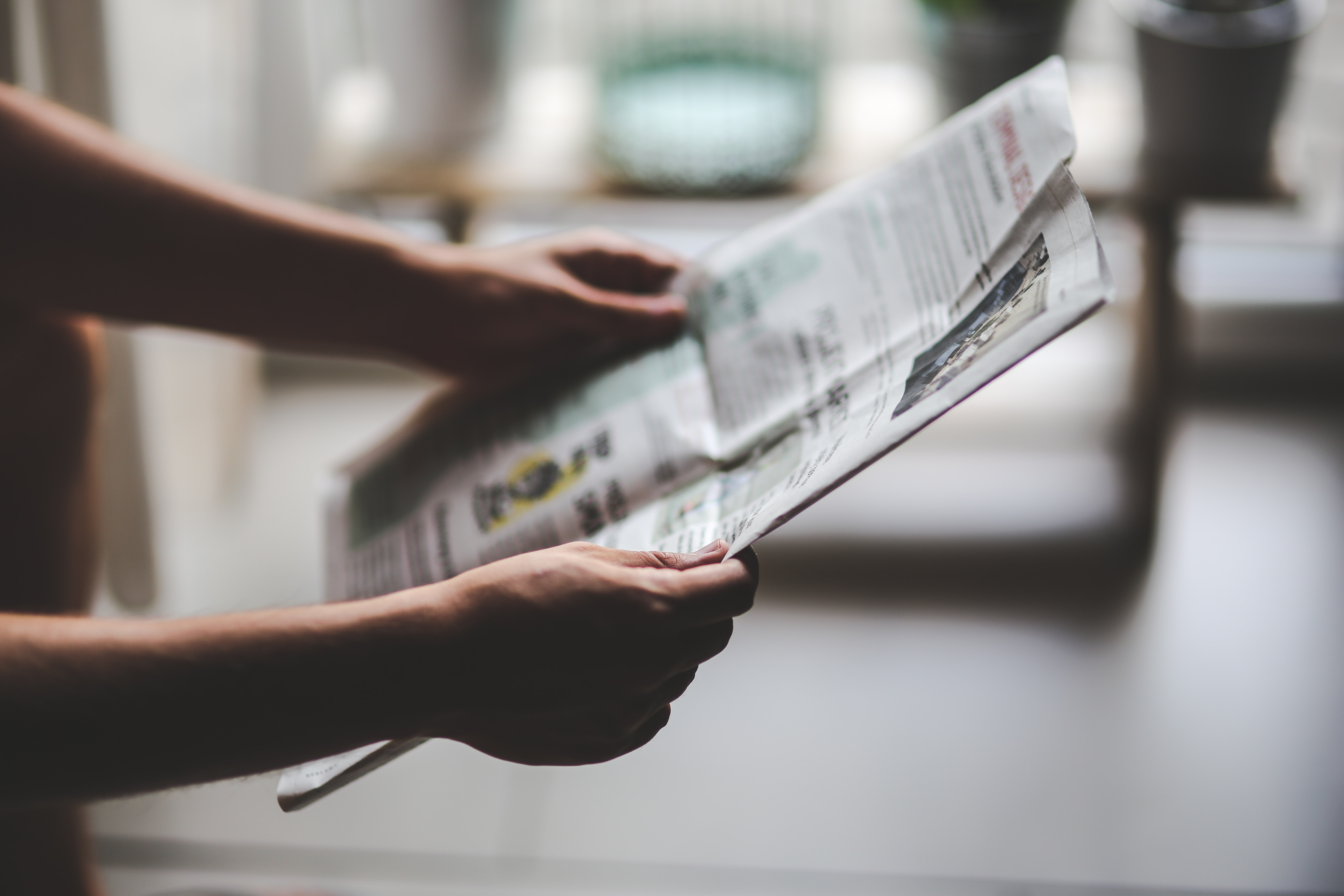 A pair of hands holds a newspaper.