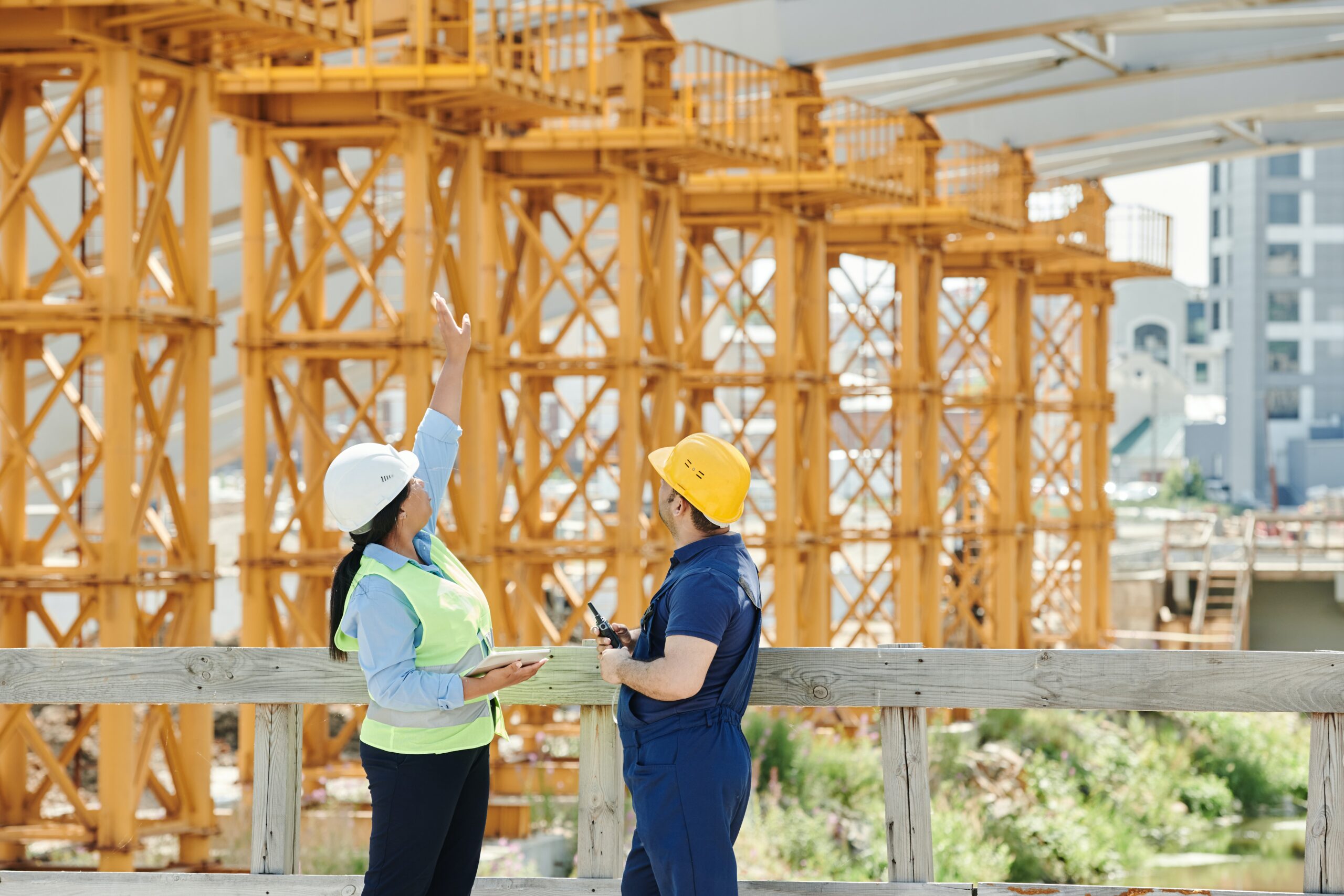 Man and woman in hardhats talking at construction site.