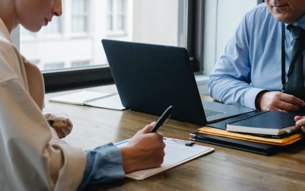 Woman writing notes at desk during meeting.