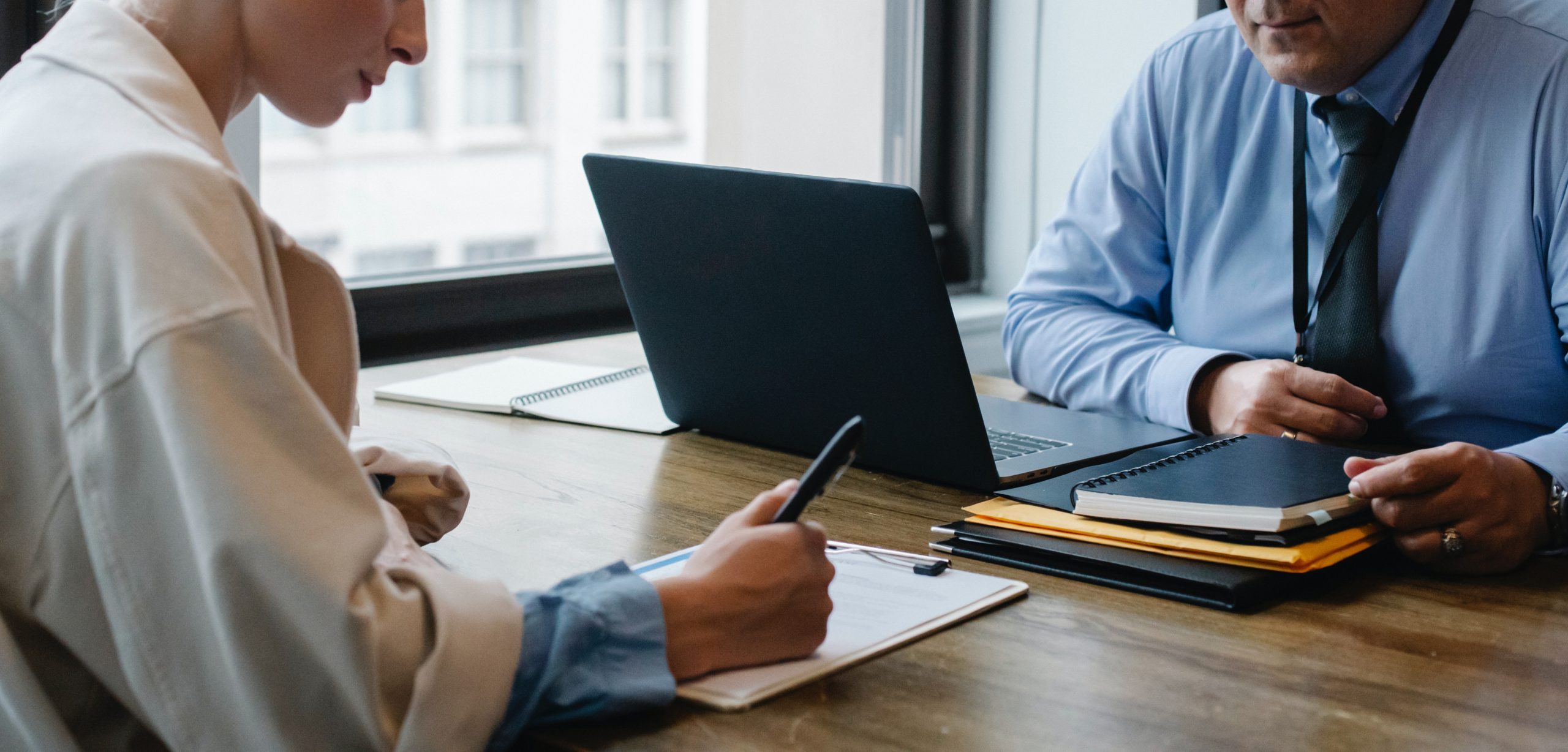 Woman writing notes at desk during meeting.