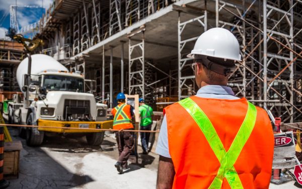 Man in hard hat with back turned faces construction site.