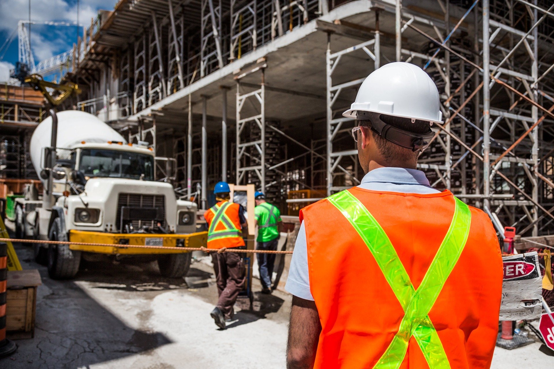 Man in hard hat with back turned faces construction site.