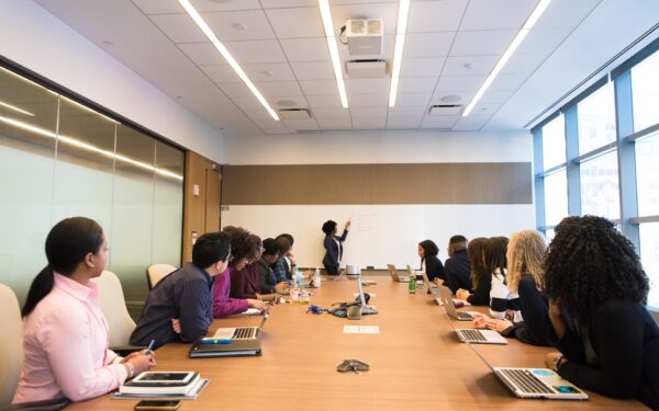 Group of people sitting at conference table watching presentation.