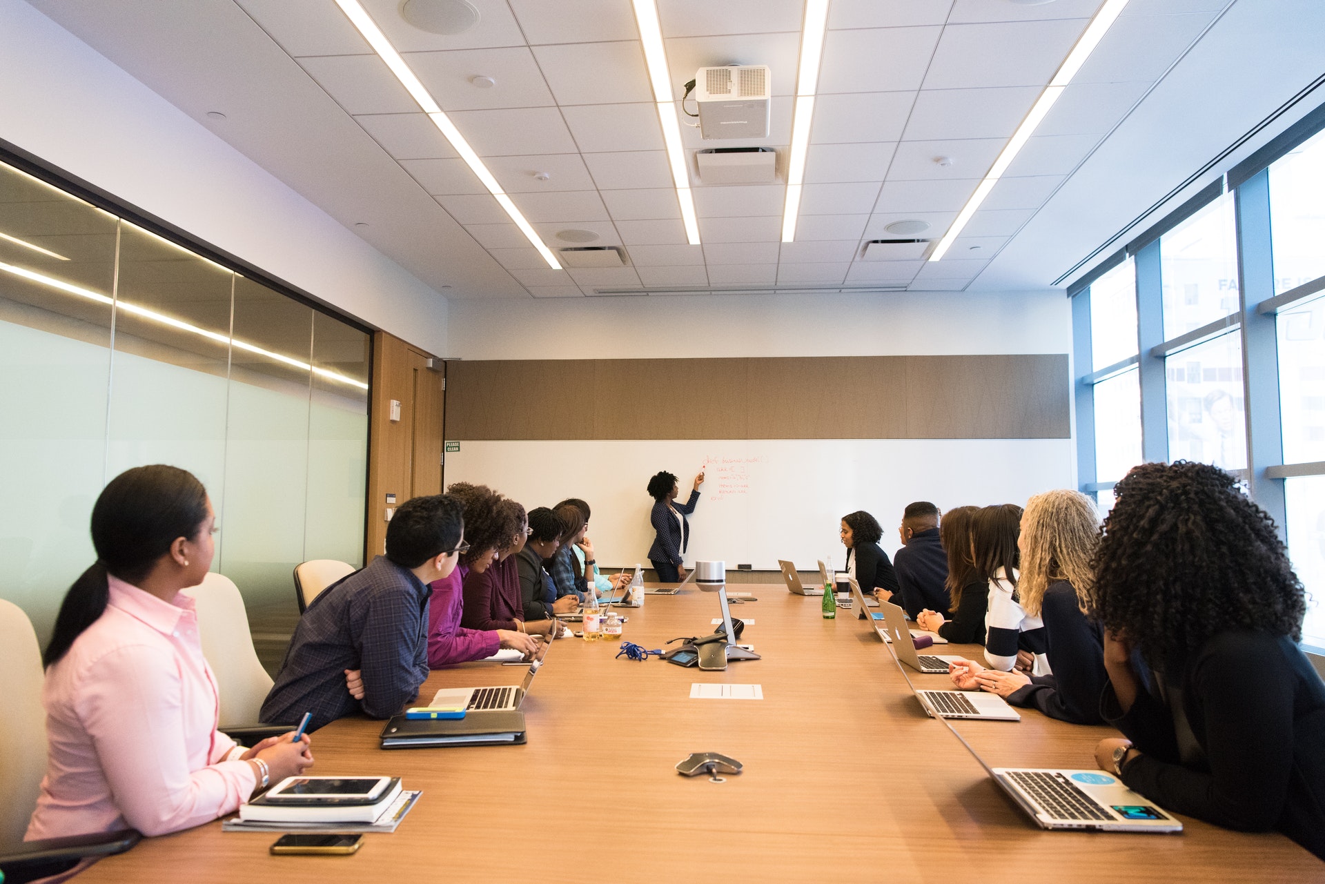 Group of people sitting at conference table watching presentation.