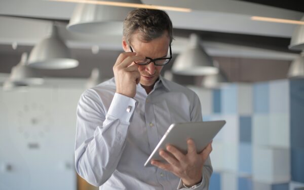 Man in glasses holding ipad.