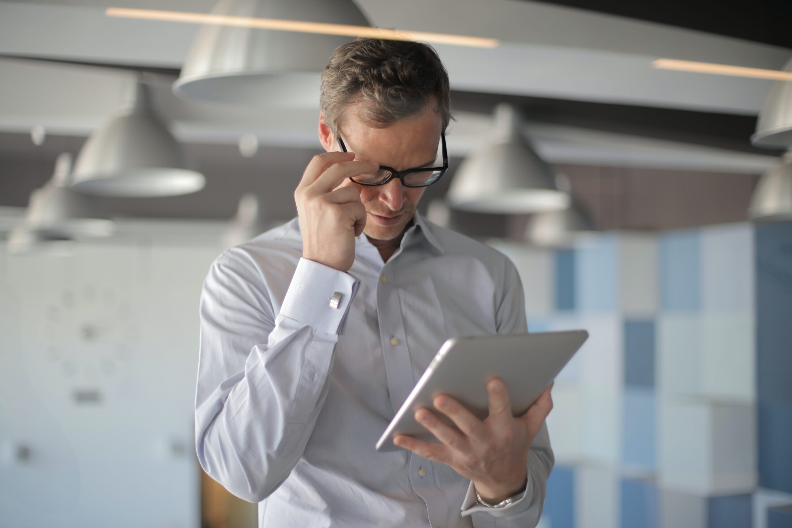 Man in glasses holding ipad.