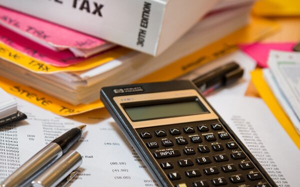 Calculator sitting on top of paperwork next to income tax book.