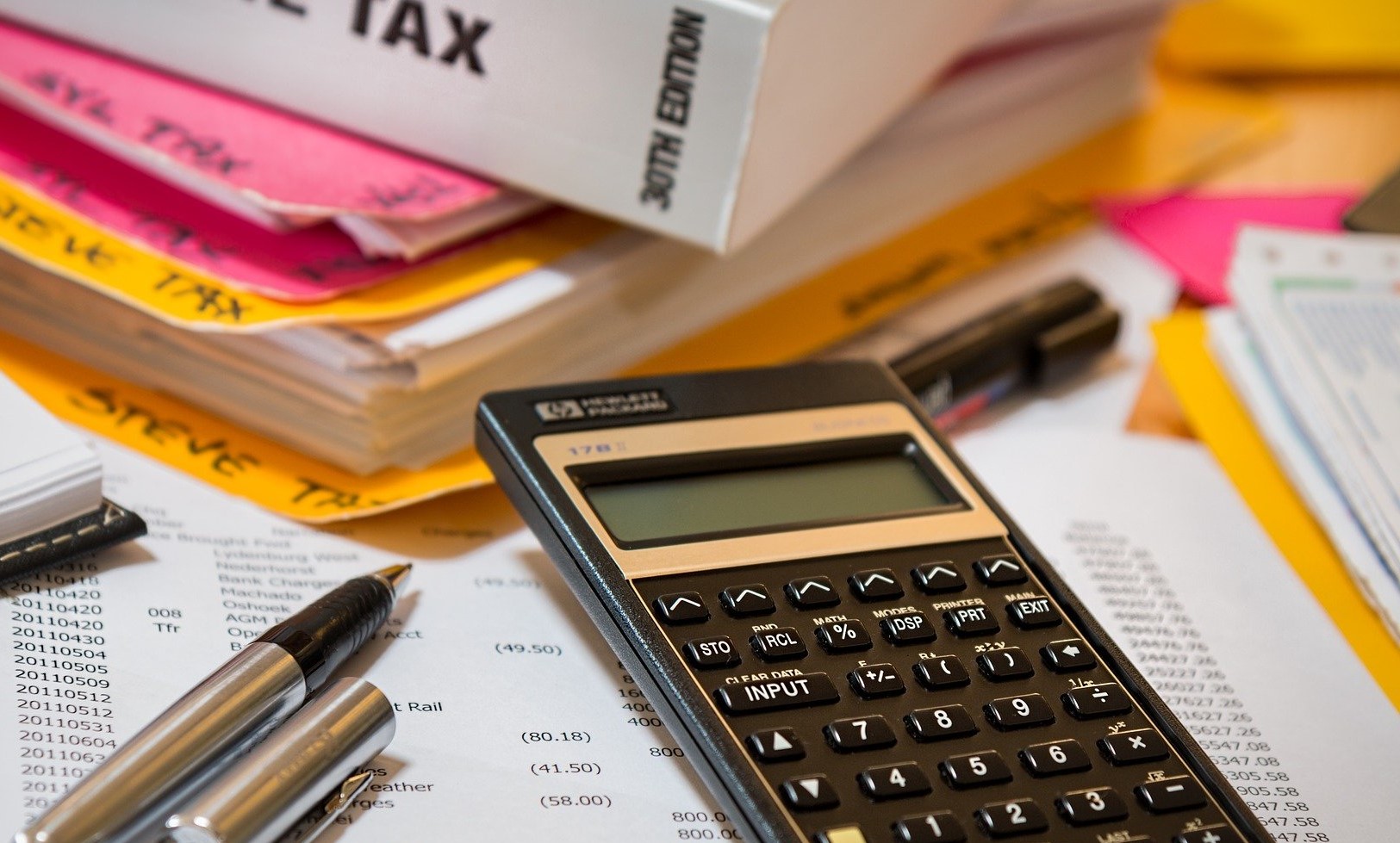 Calculator sitting on top of paperwork next to income tax book.