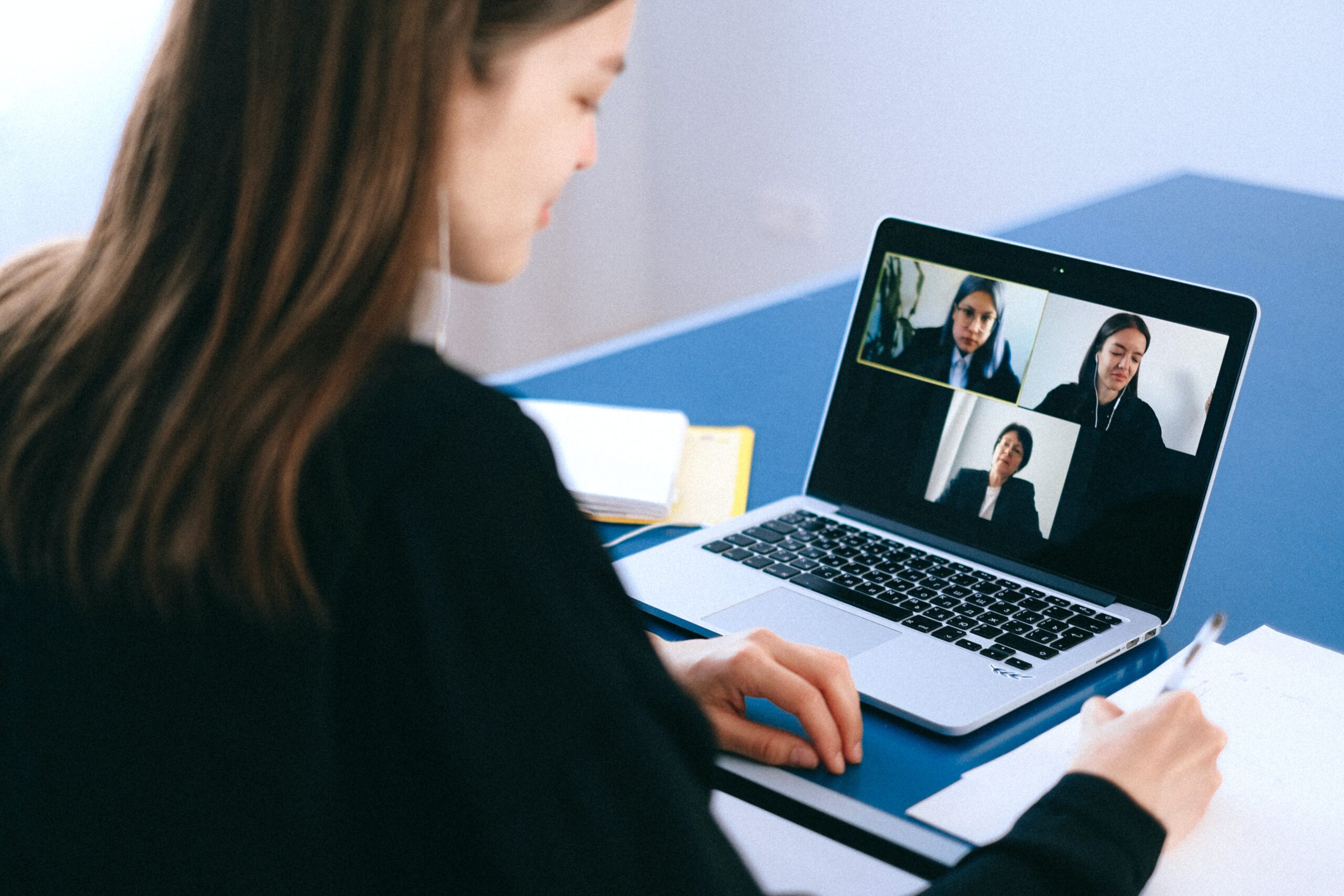 Woman sitting at desk on video call on laptop.