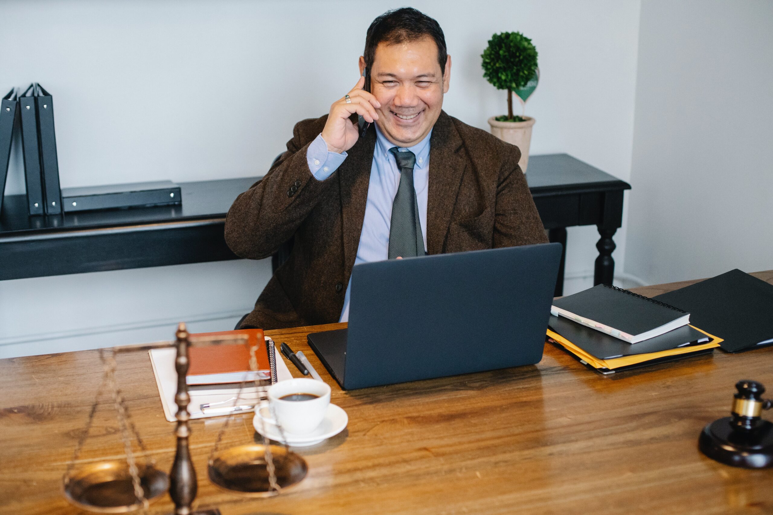 Man smiling while on sitting at desk and talking on the phone.