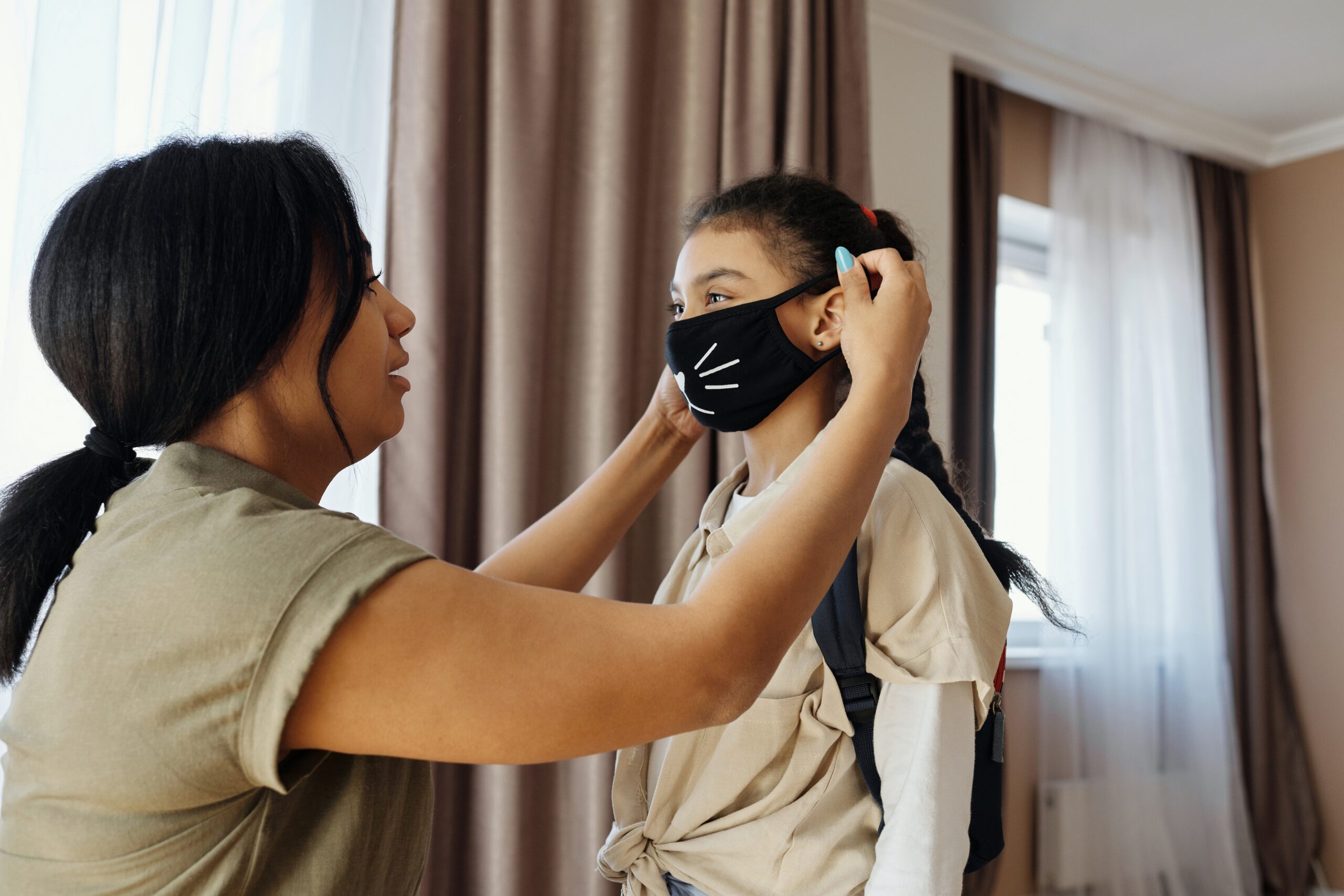 Mother putting mask on daughter.