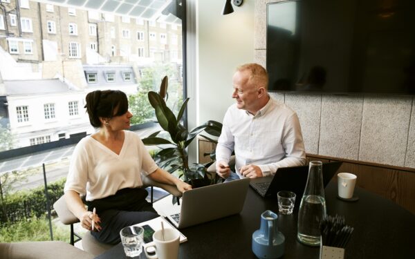 Man and woman having a meeting with two laptops.