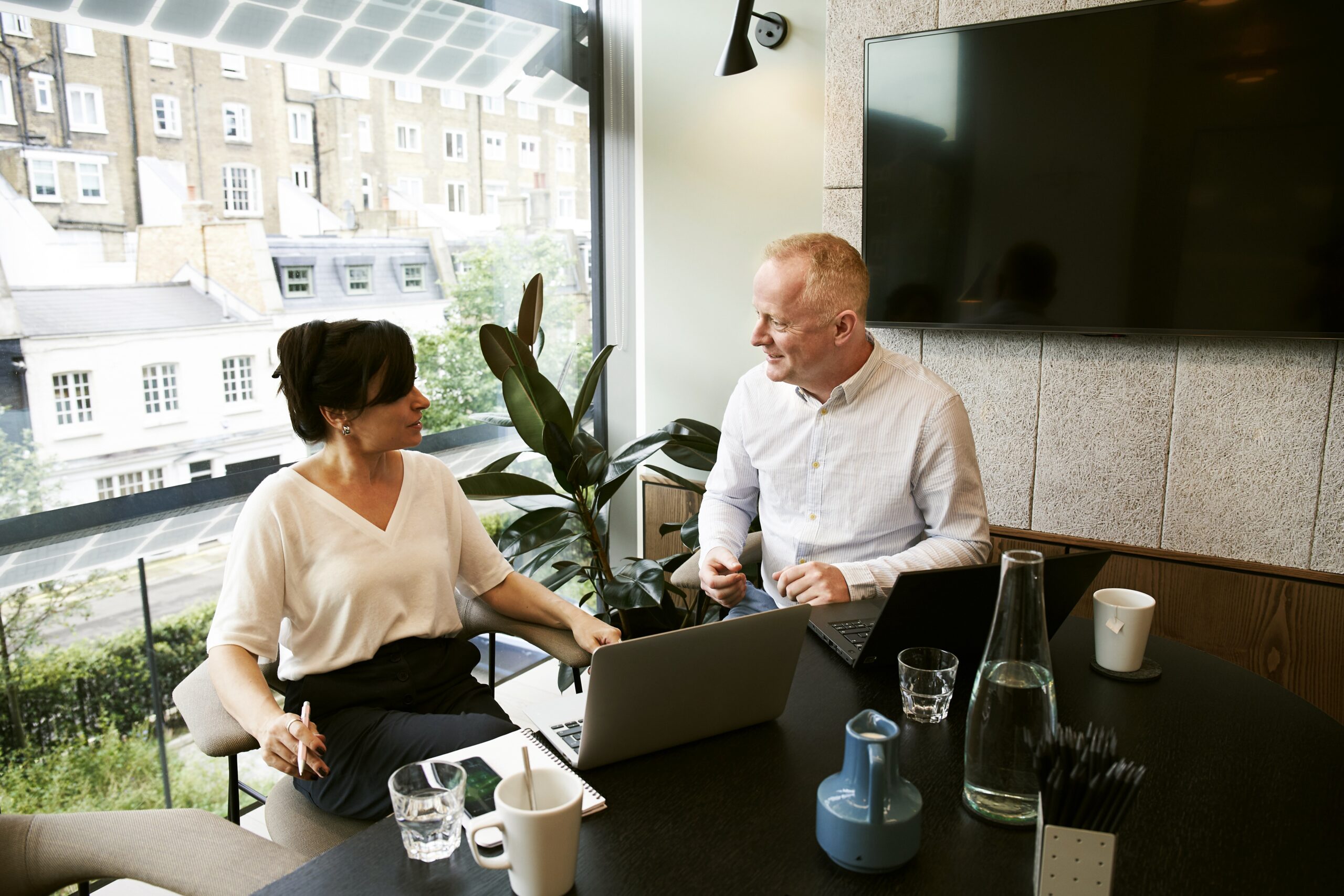 Man and woman having a meeting with two laptops.