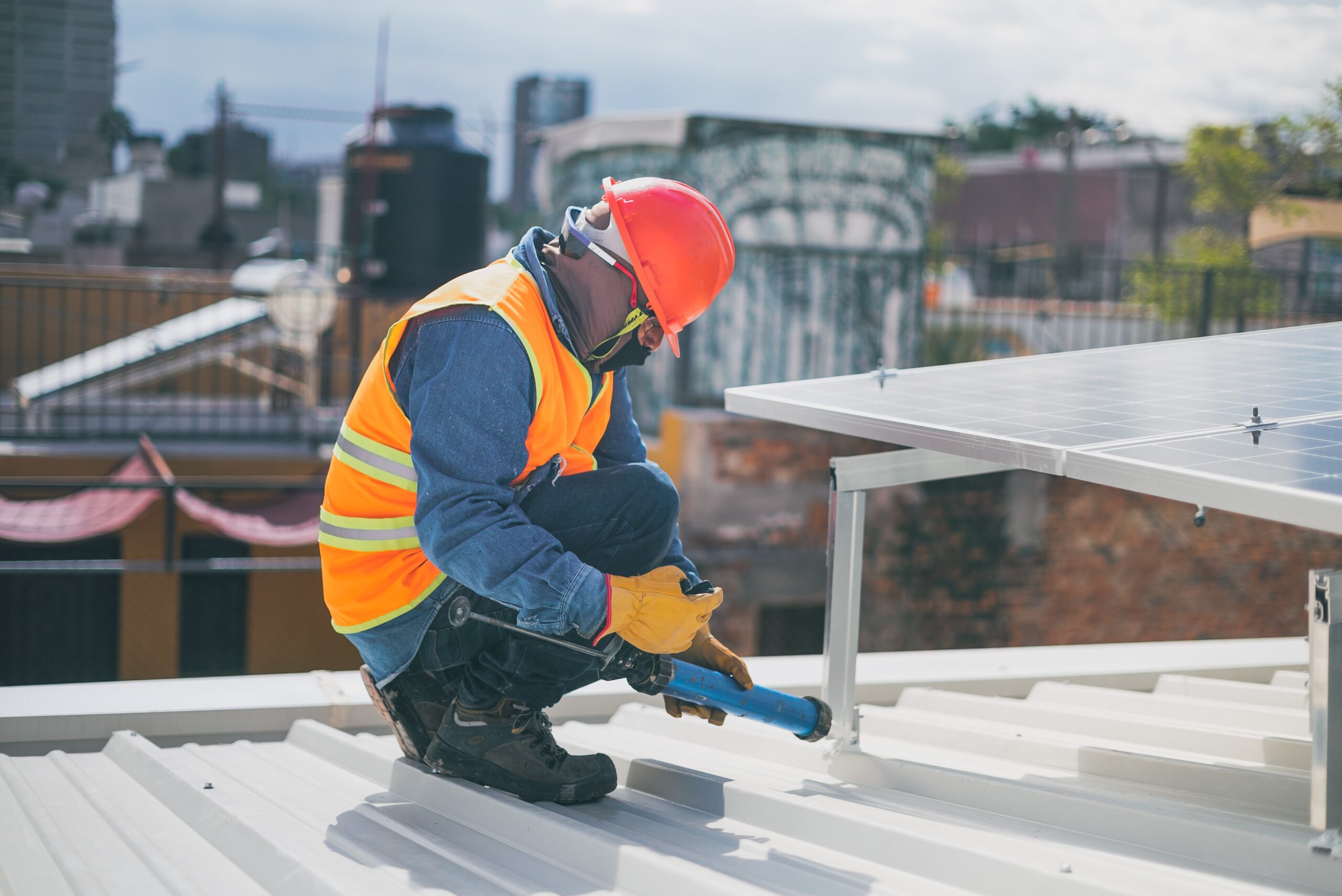 Man kneeling on roof installing solar panels.