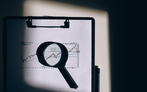 magnifying glass laying on top of chart on clipboard