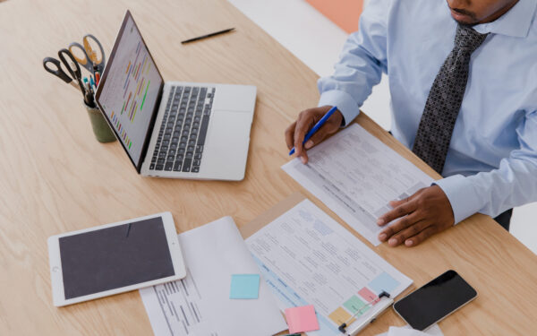 Man working at desk with papers laptop and ipad.