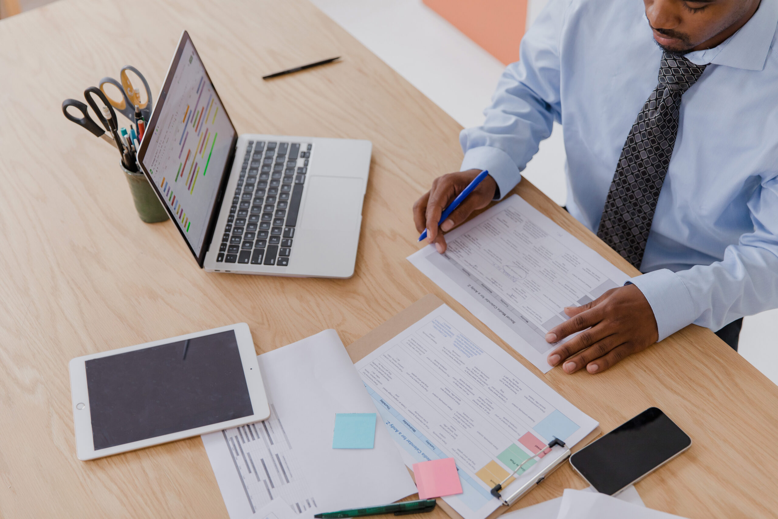 Man working at desk with papers laptop and ipad.