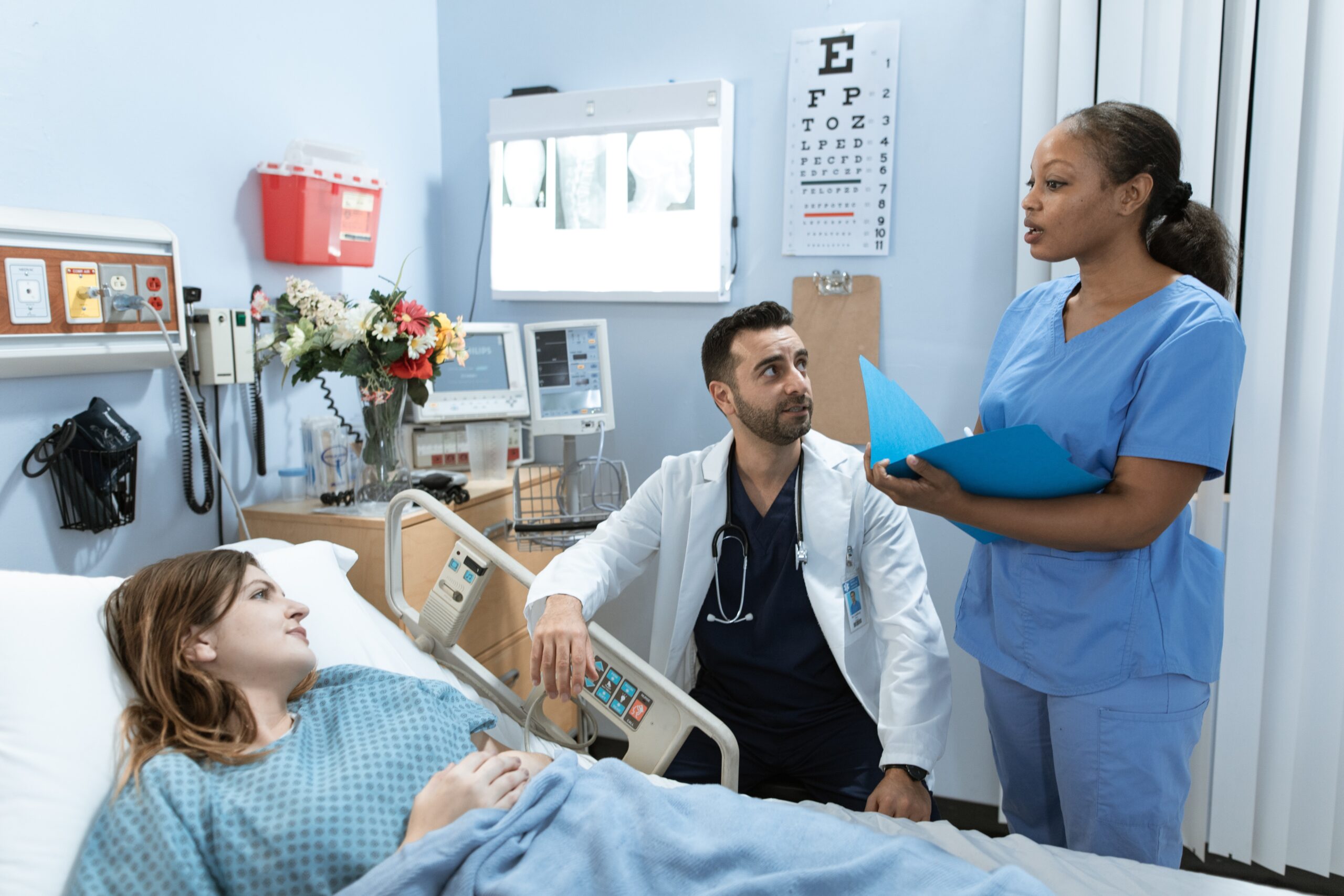 Woman lying in hospital bed talking with two doctors.