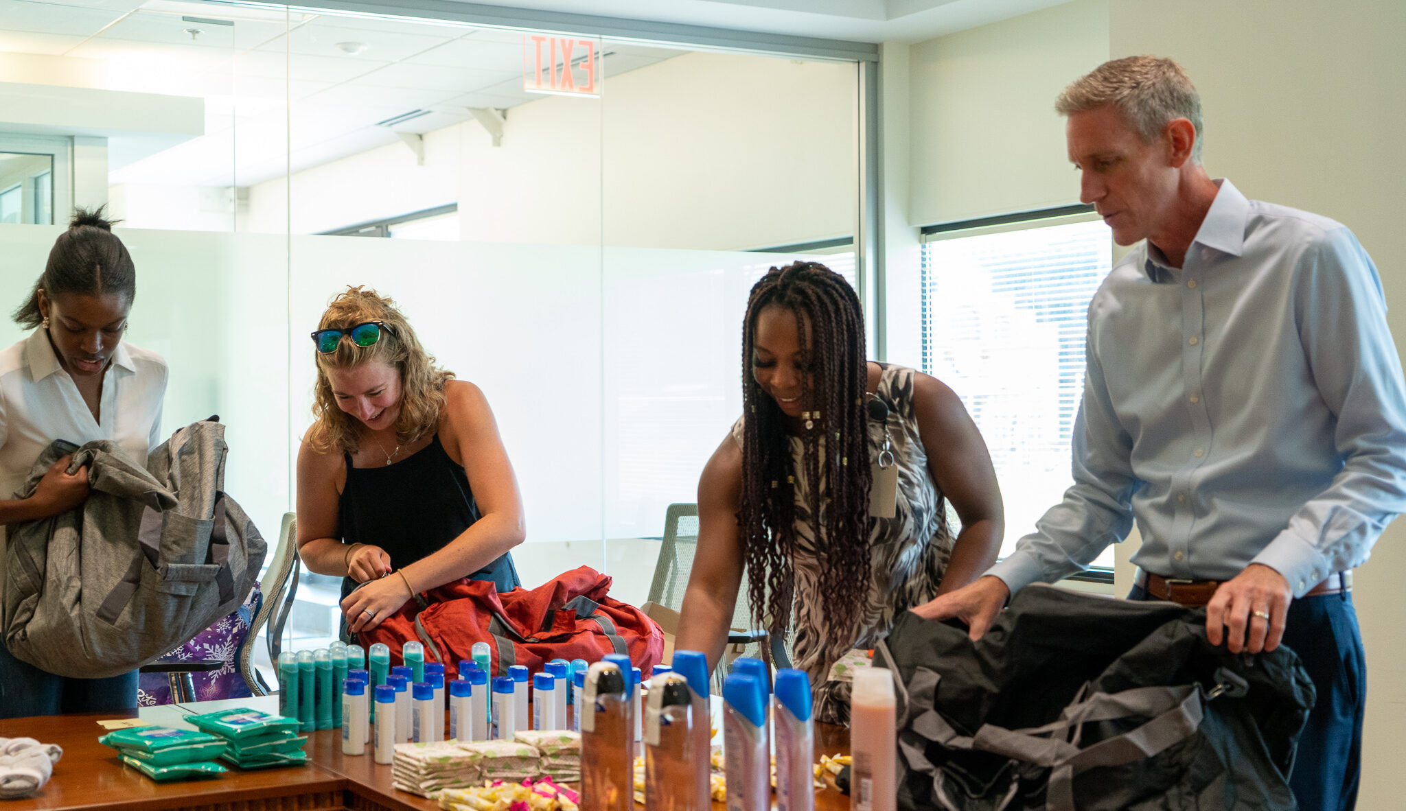 Four people packing toiletries into duffle bags.