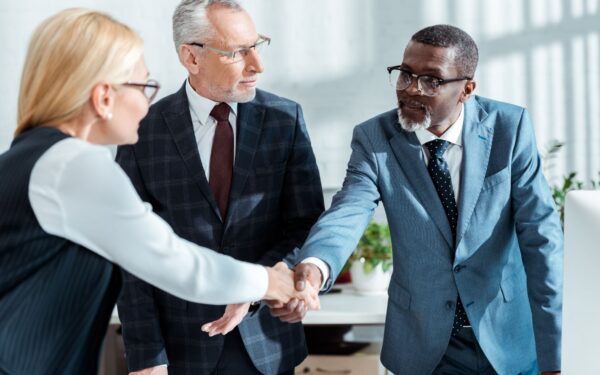 selective focus of business man shaking hands with blonde woman in office