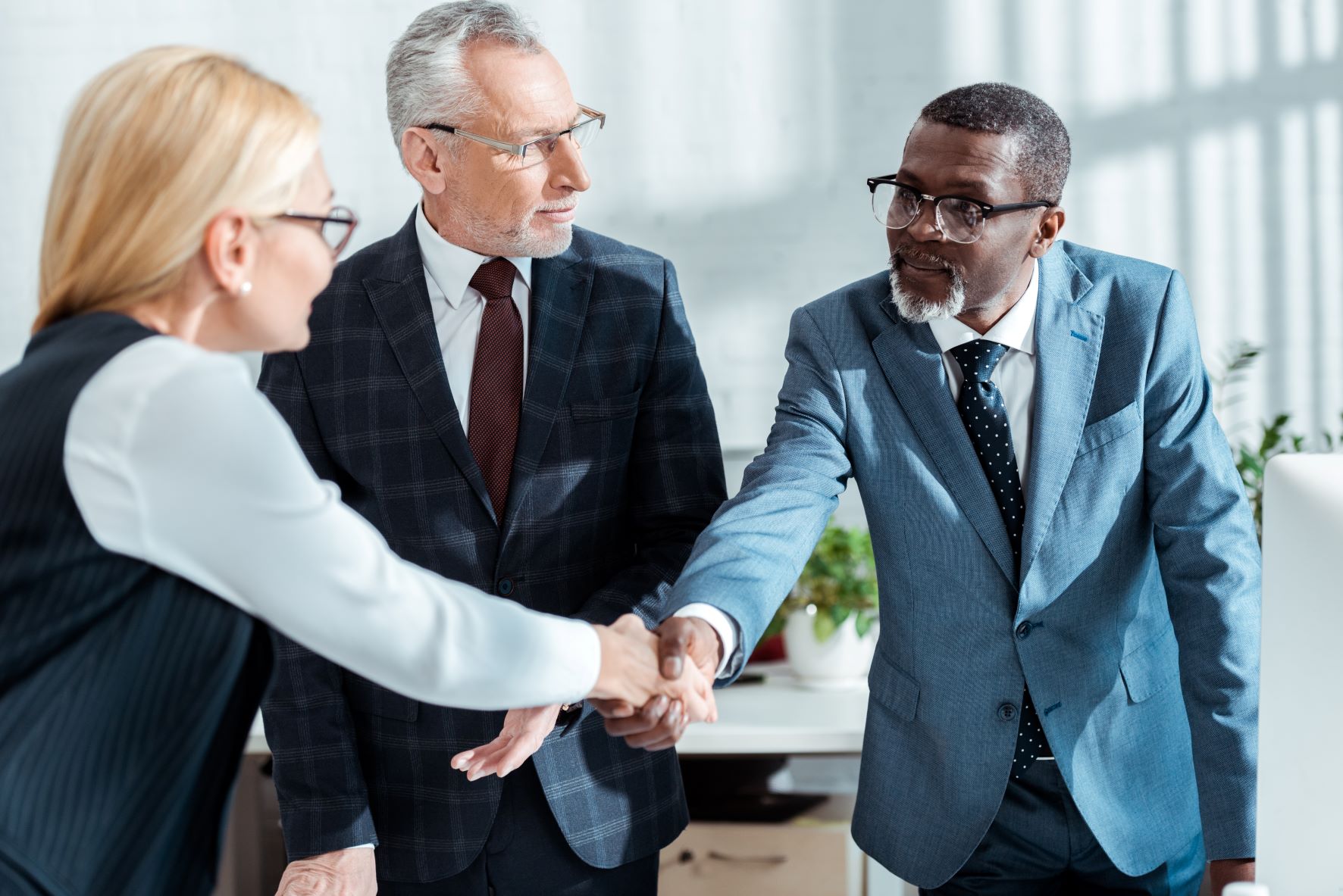 Business man shaking hands with blonde woman in office.