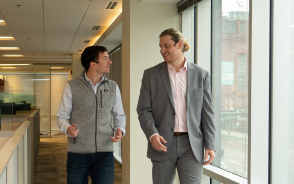 Corporate Finance Supervisor Cazmier Tymoch stands talks to Audit & Accounting Supervisor Pat St. Clair by cubicles