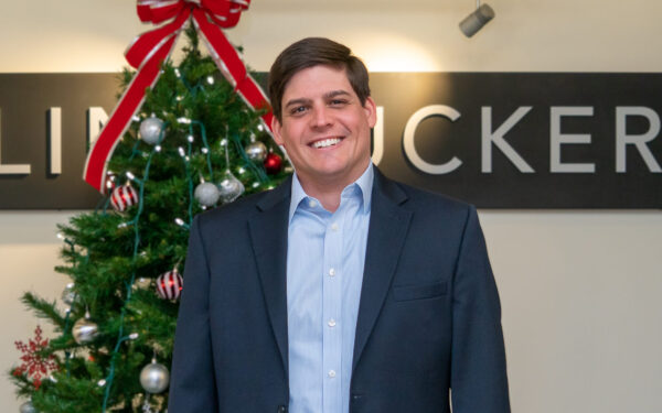 Ellin & Tucker directo Zach Bromwell stands in front of Christmas tree in the Eliin & Tucker lobby