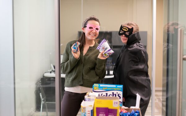 Grace Wickwire poses with a Supergirl mask next to Alex McClellan dressed as Batman in the Ellin & Tucker office