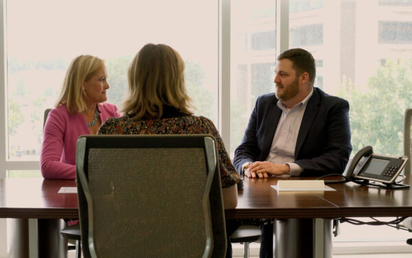 A man and a woman sit across a conference table from an interviewee.