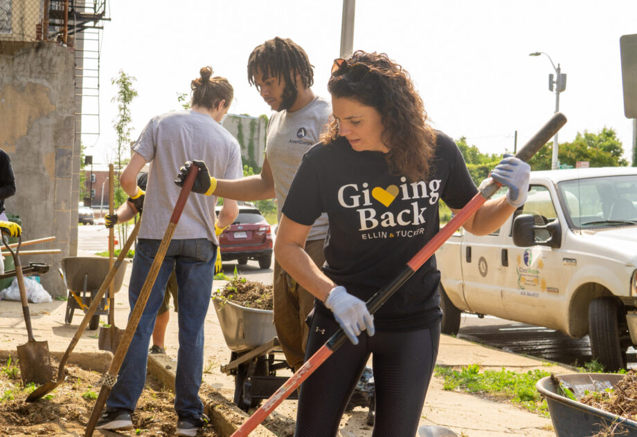 Woman uses shovel to dig in a garden in Baltimore City.