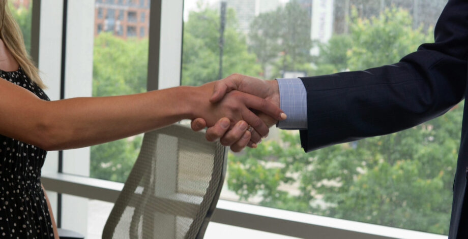 A man and a woman shaking hands in a conference room.