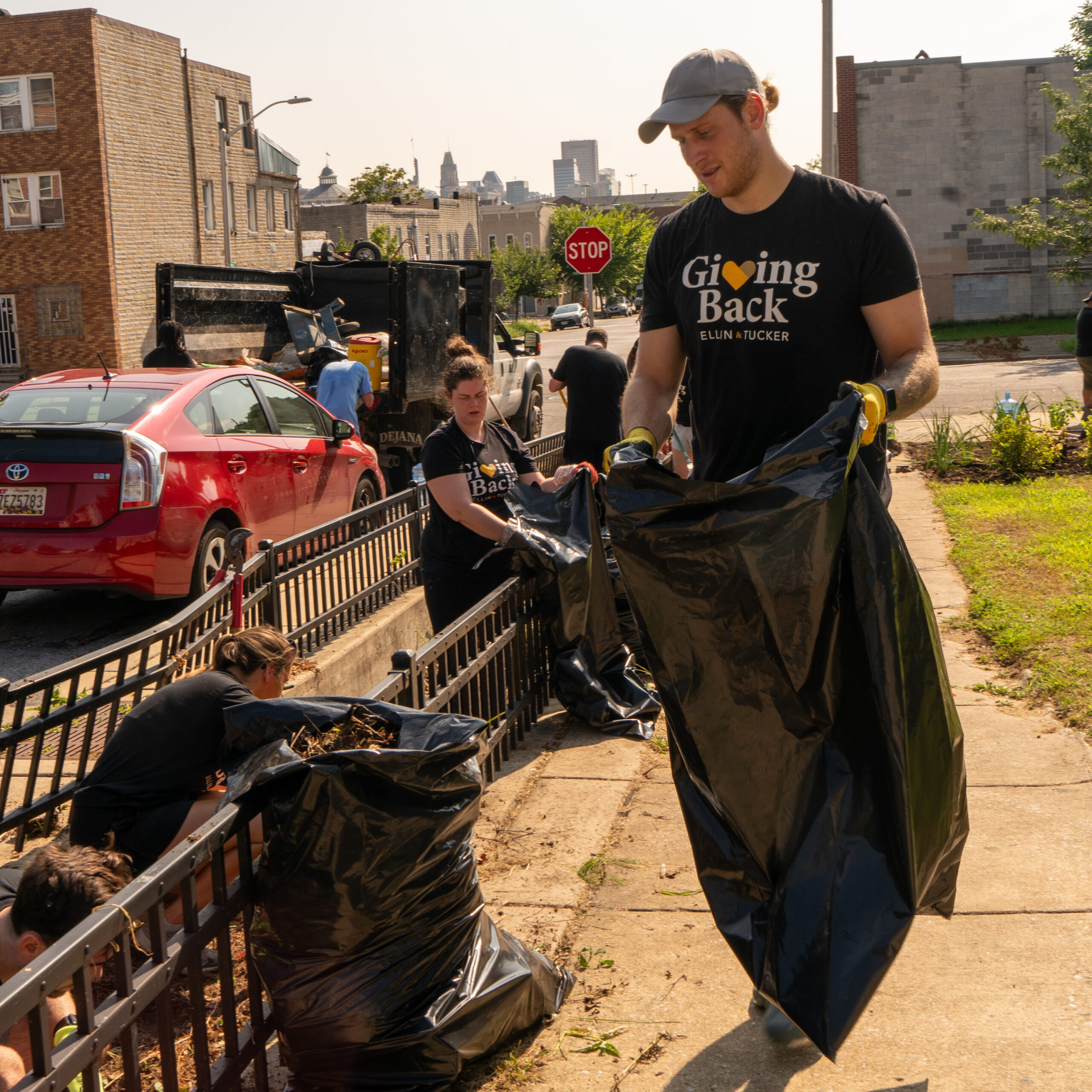 Man holds a trash bag while picking up trash in a park.