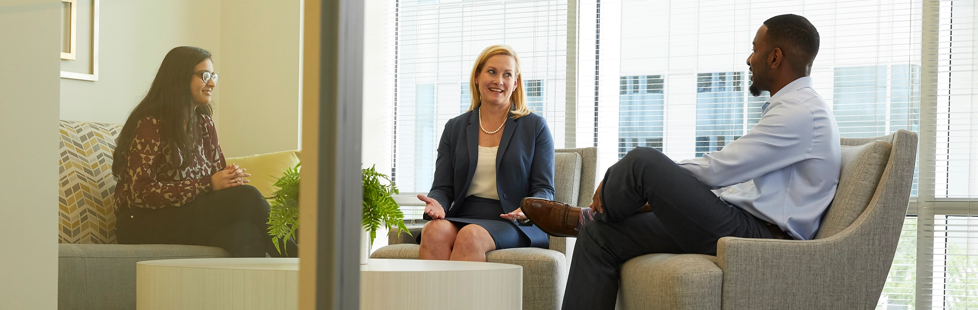Aileen Eskildsen sits in conference room with two young Ellin & Tucker employees talking.