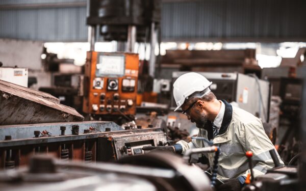 Man in hard hat working at an industrial machine.