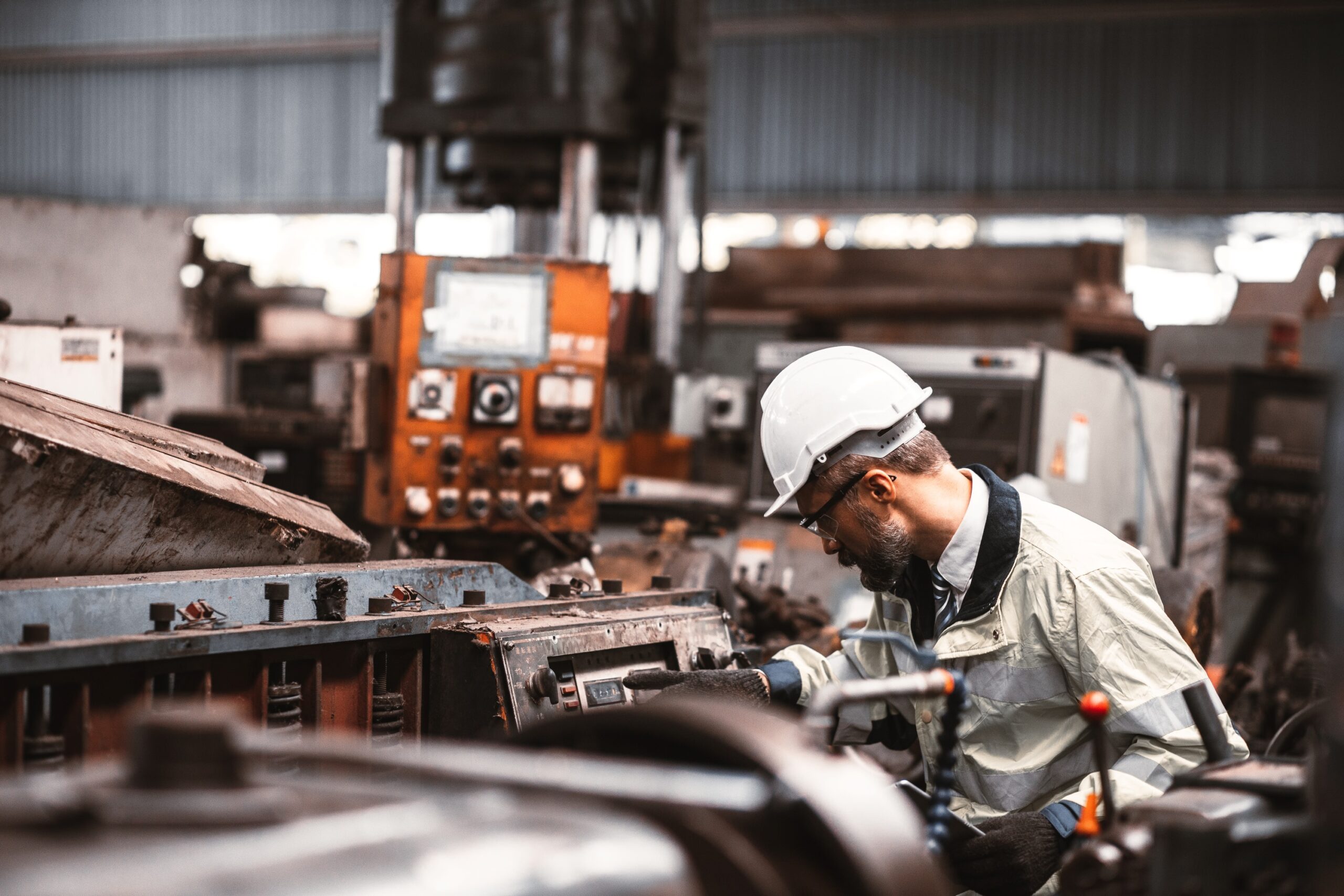 Man in hard hat working at an industrial machine.