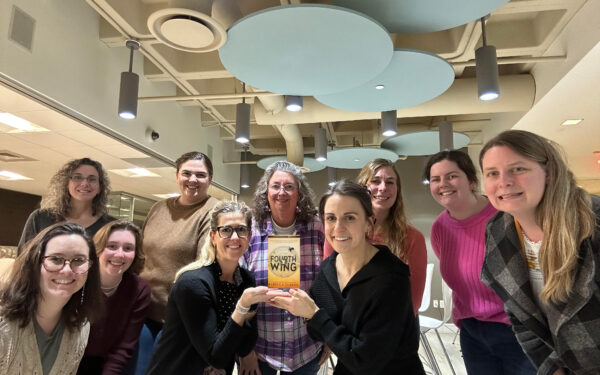 Ellin & Tucker book club poses with a copy of Fourth Wing by Rebecca Yarros