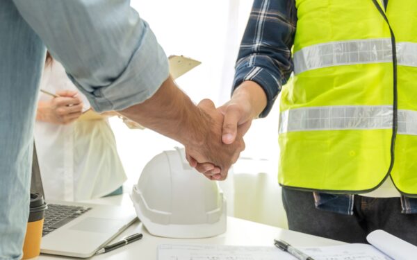 Man in yellow construction vest shakes hand of man in button up shirt