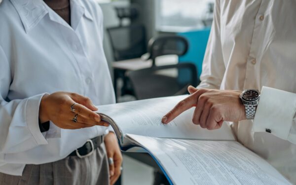 people in white button up shirts pointing at papers in a folder