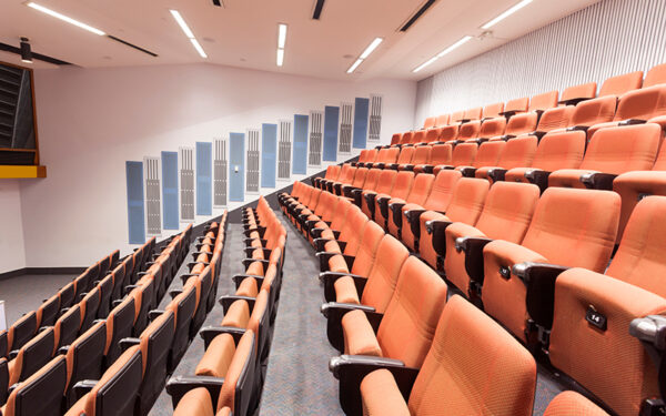 rows of orange chairs in lecture hall with fluorescent lights